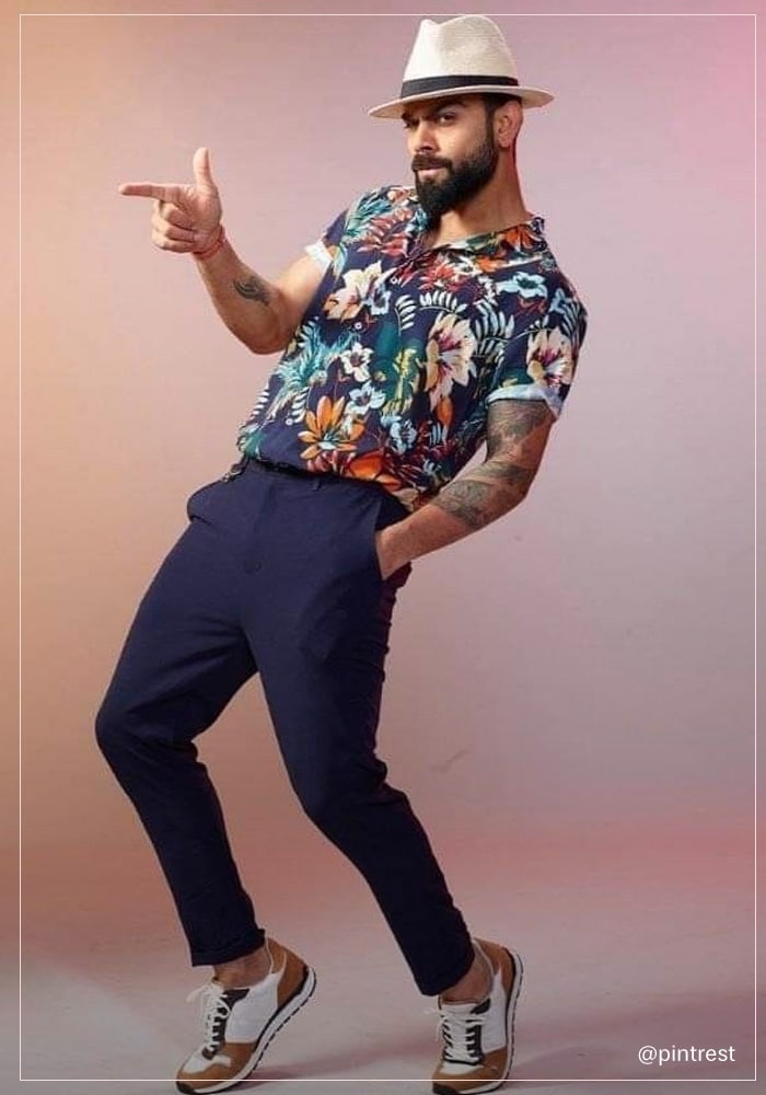Virat kohli wearing floral printed shirt paired with navy blue chinos, sneakers and hat
