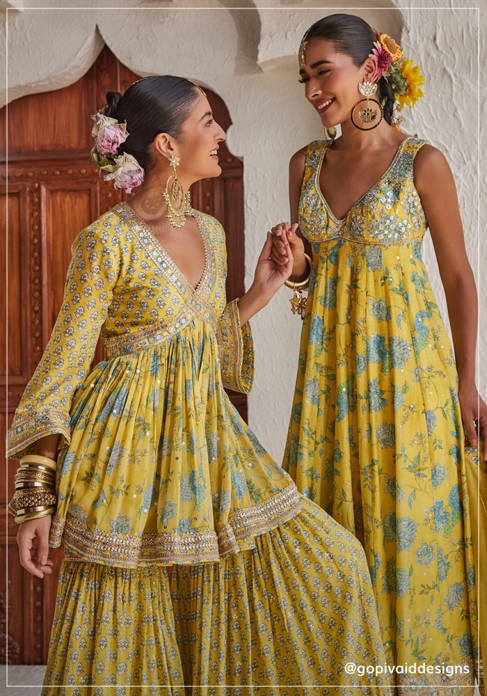 Two models wearing Gopi Vaid outfits. One wearing a ethnic maxi dress and the other wearing a peplum kurta with sharara