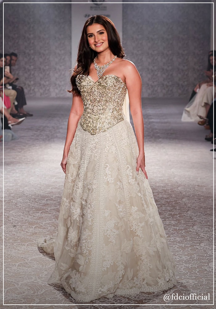 Tara Sutaria walking the runway for Suneet Varma in an ivory corset and skirt set