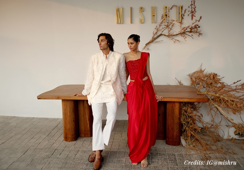Male-model-wearing-white-bandhgala-set-and-female-model-wearing-red-pre-draped-dhoti-saree.jpg