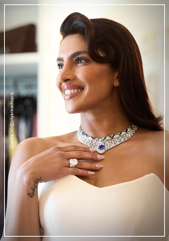 Priyanka Chopra Jonas in white robe wearing Bvlgari diamond and 
sapphire necklace during Oscars 2026 getting ready session