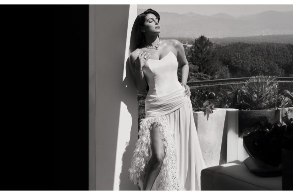 Priyanka Chopra Jonas in custom white Dior gown with feather hemline and thigh high slit posing on outdoor terrace before Oscars 2026