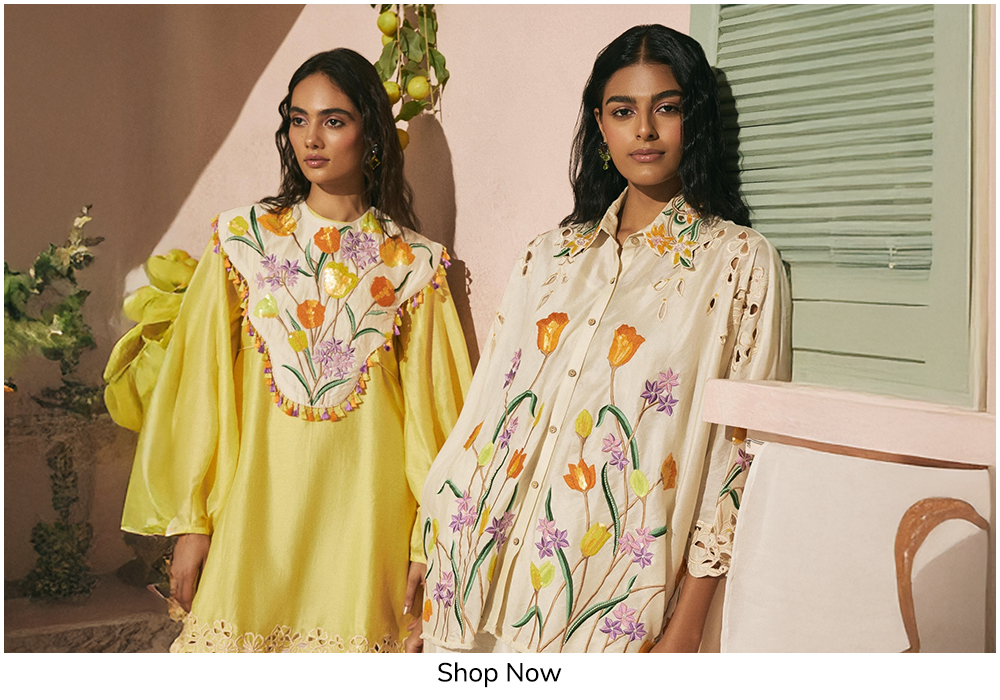 Two women wearing pastel floral embroidered designer dresses with statement sleeves and handcrafted detailing, styled for an elegant Mahjong party